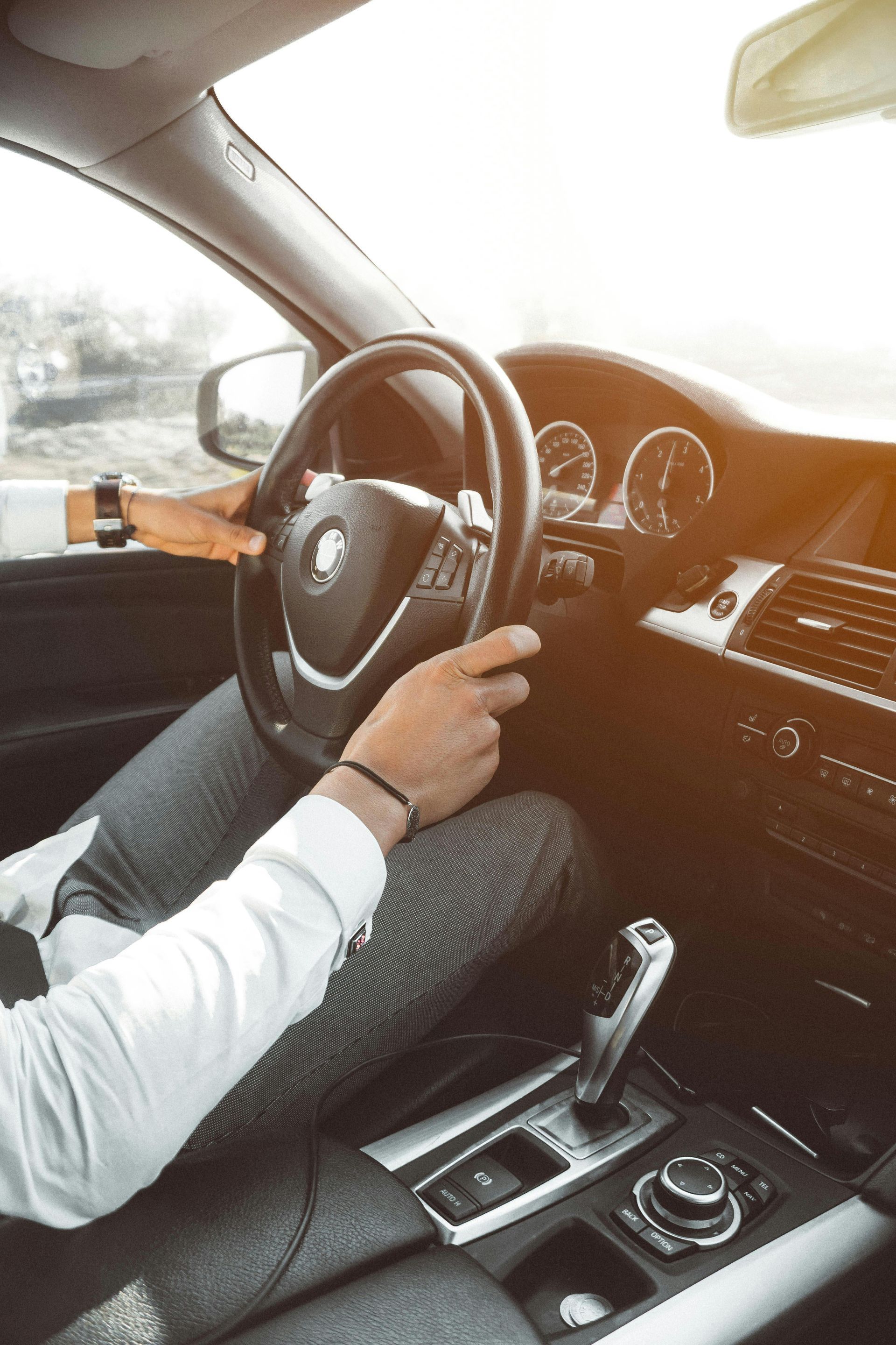 Ein Mann fährt mit überkreuzten Beinen Auto.