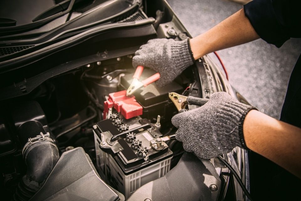 Eine Person lädt eine Autobatterie mit einem Ladegerät auf.