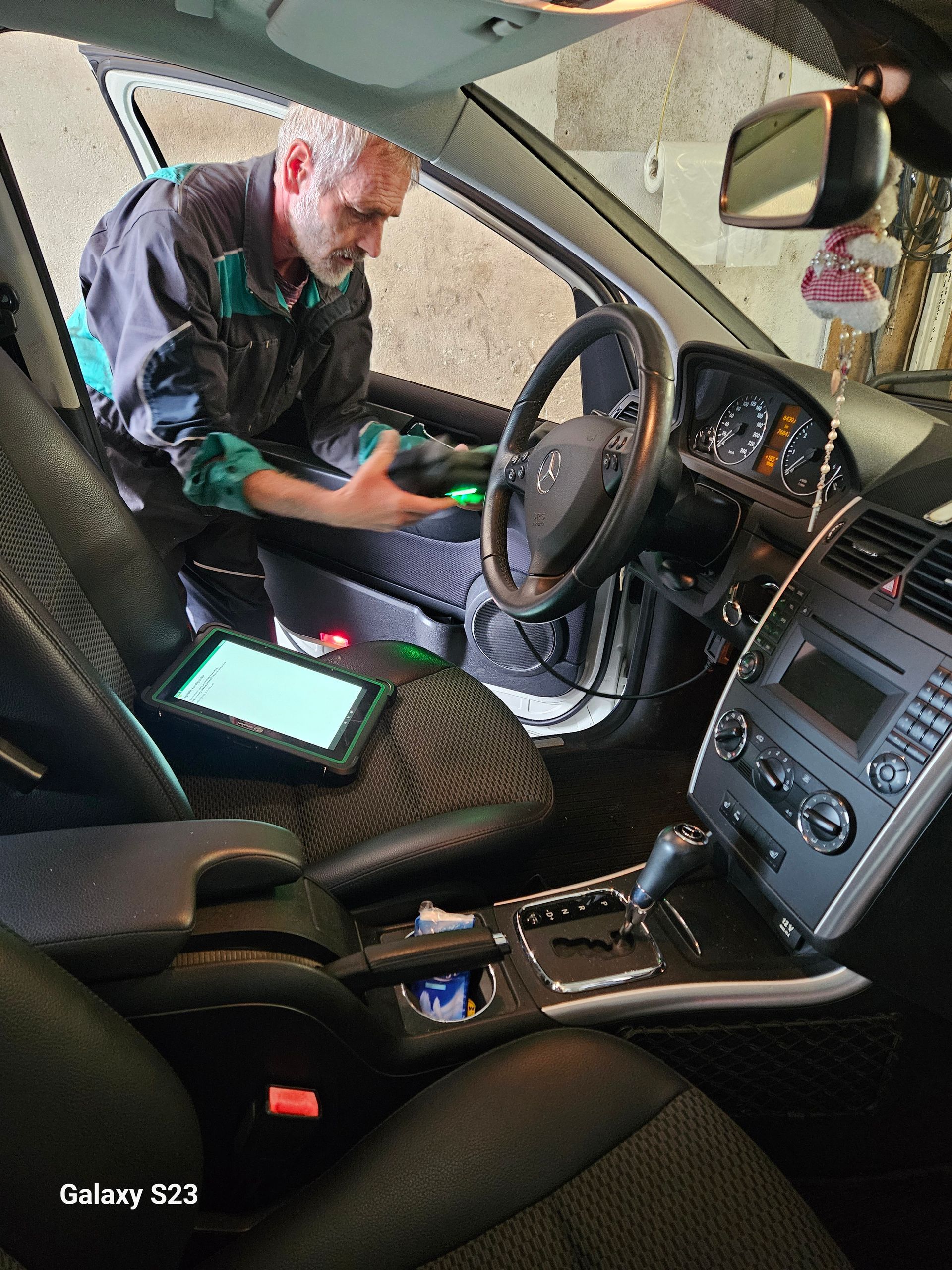 Un mécanicien diagnostique une voiture Mercedes à l'aide d'une tablette de diagnostic à l'intérieur 