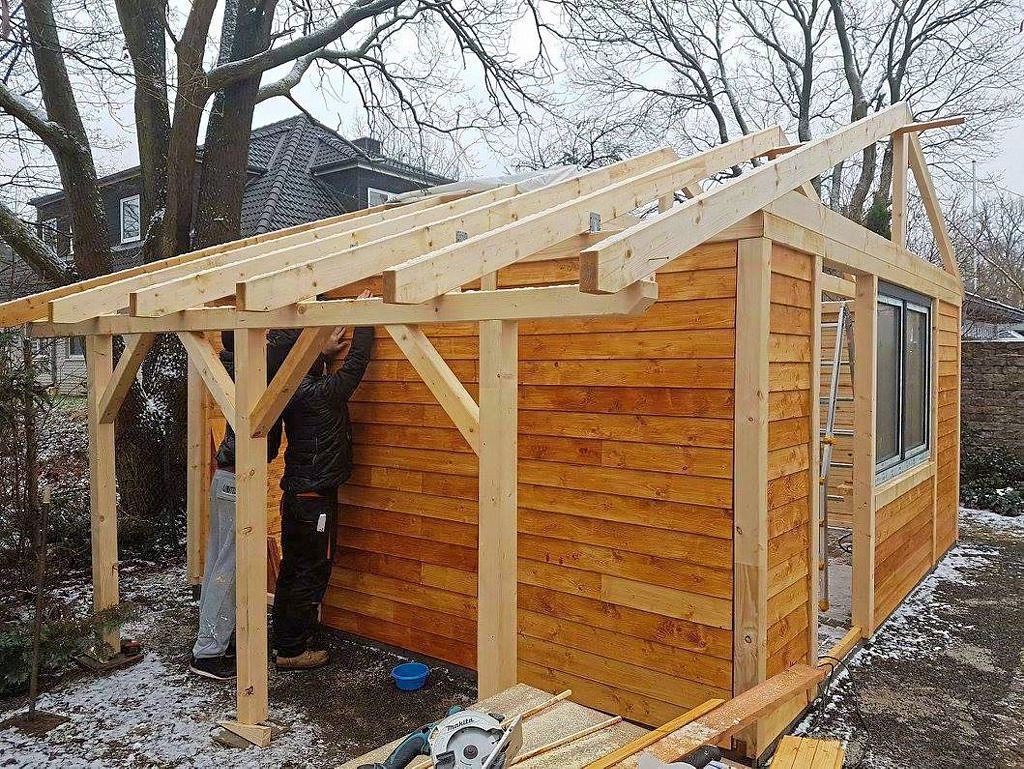 Zwei Männer arbeiten an der Seitenwand des Gartenhauses aus Holz