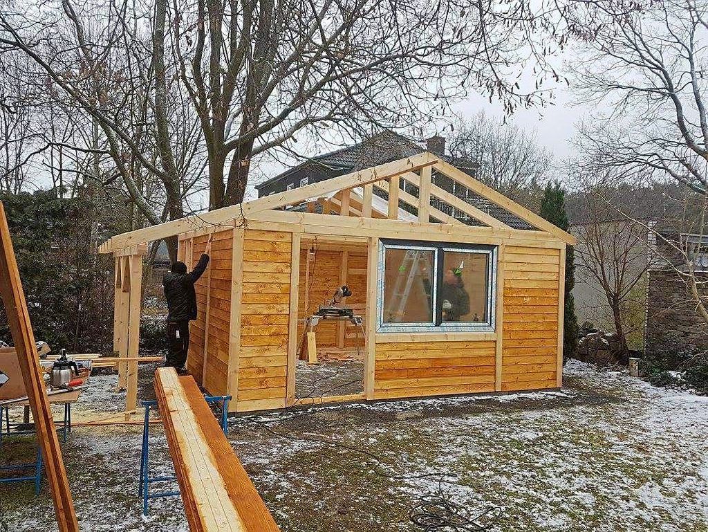 Grundgerüst mit ersten Holzwänden und eingesetzten Fenstern eines Gartenhauses