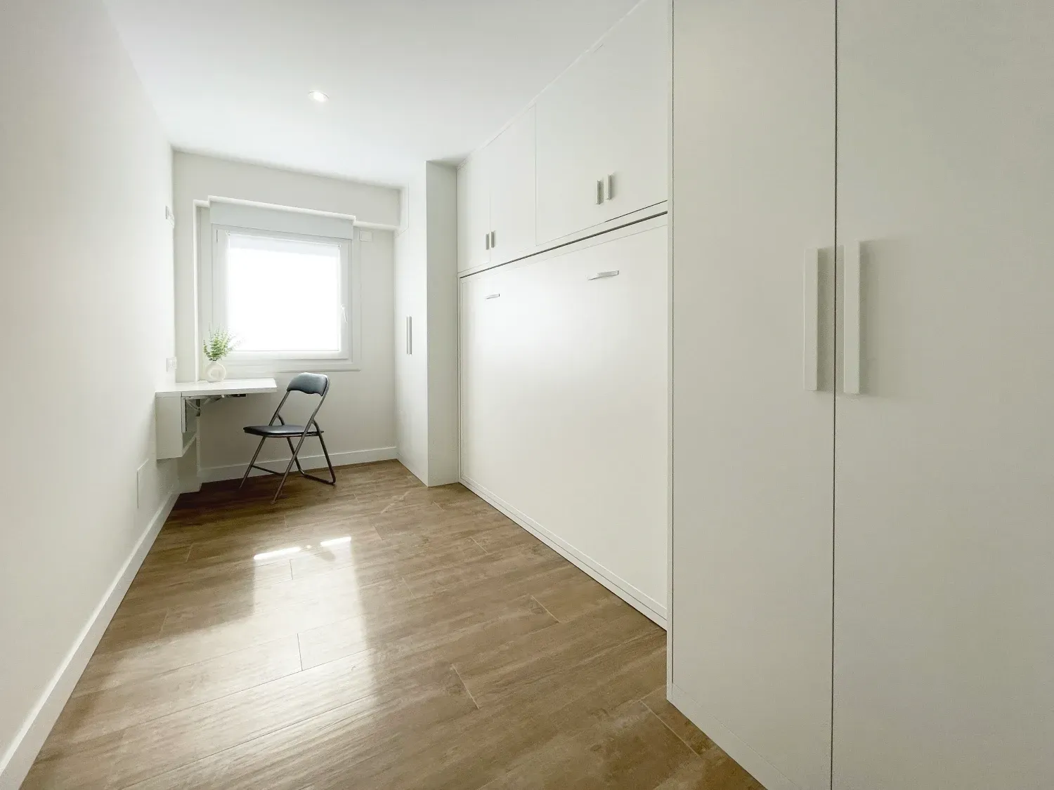 Una habitación pequeña y luminosa con suelo de imitación madera.