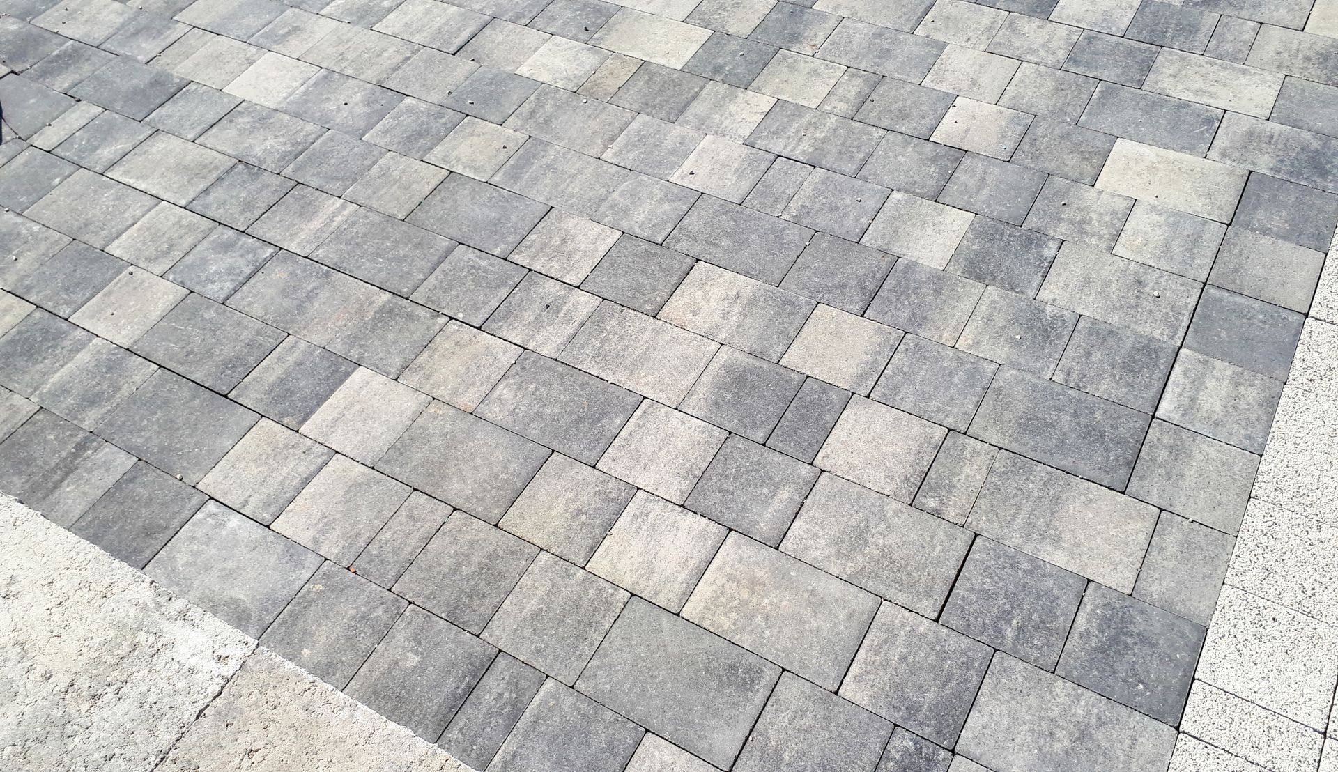 Motif de pavage en briques imbriquées grises et beiges.
