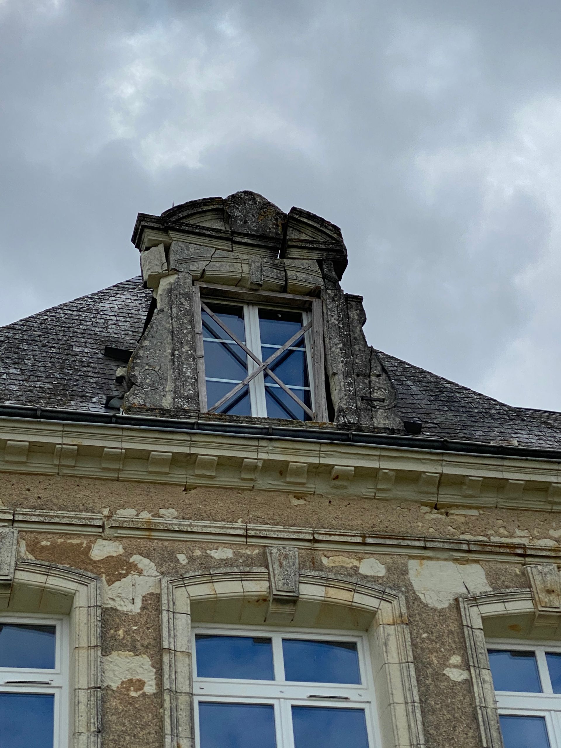 Vieux bâtiment au toit délabré et aux fenêtres condamnées.
