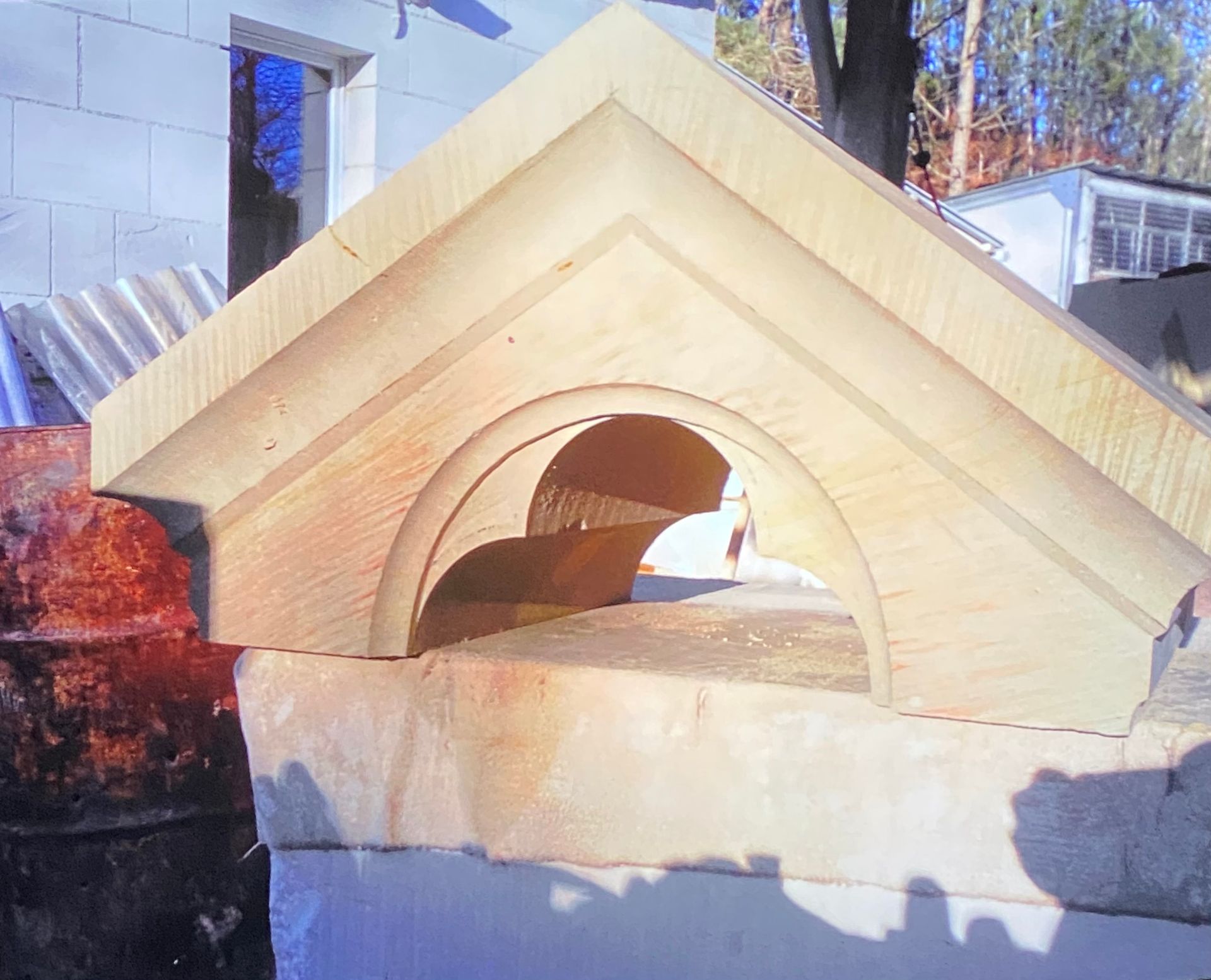 Détail architectural en bois, probablement un fronton, avec des ouvertures cintrées, reposant sur une structure en pierre.