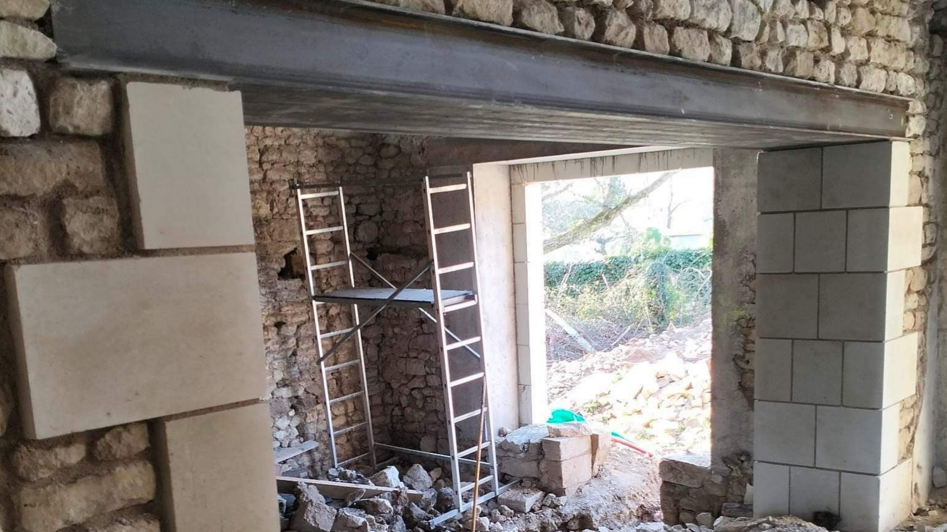Rénovation d'un mur en pierre, poutre en acier soutenant une porte.