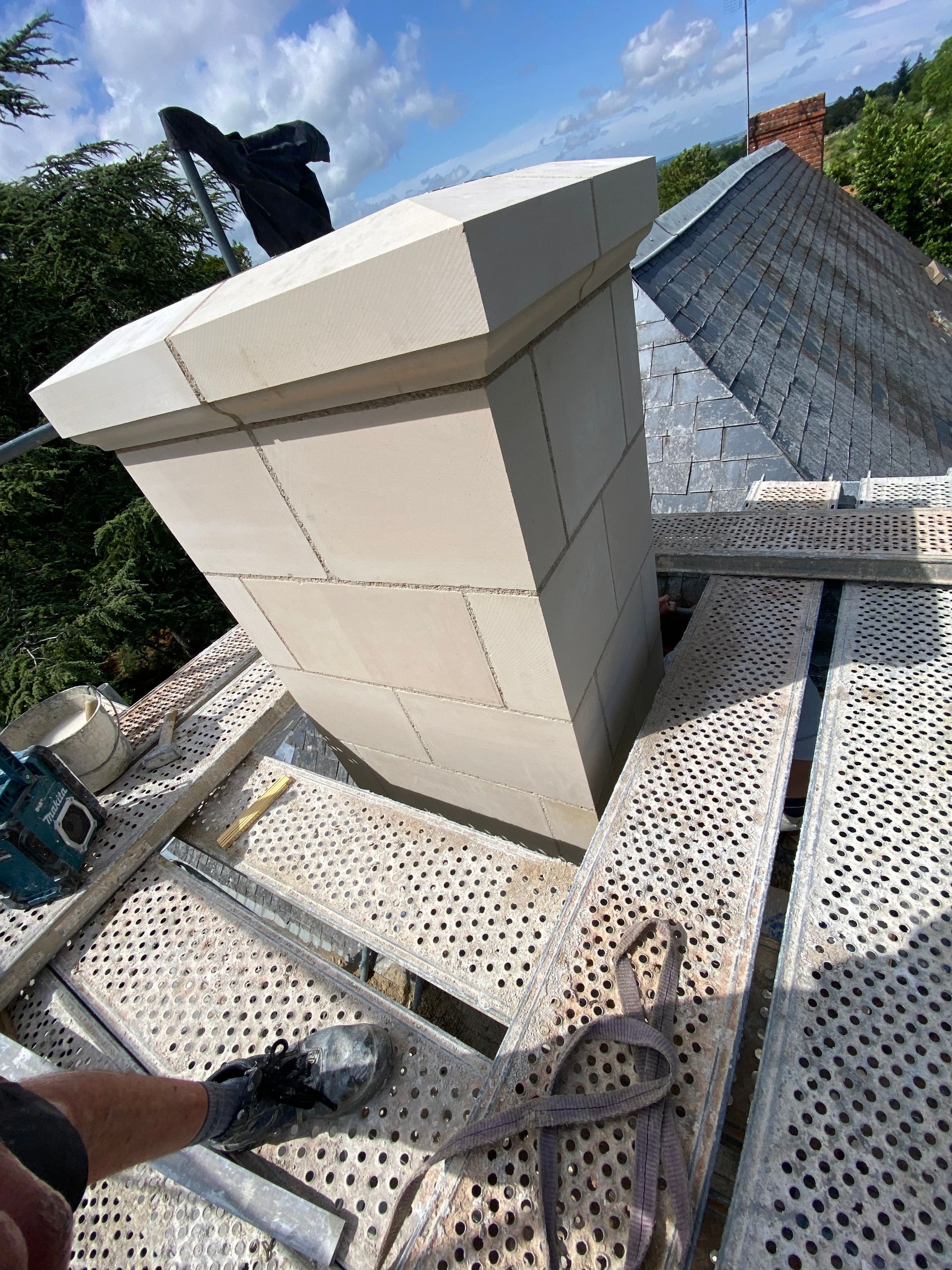 Réparation de cheminée sur un toit avec échafaudage métallique.