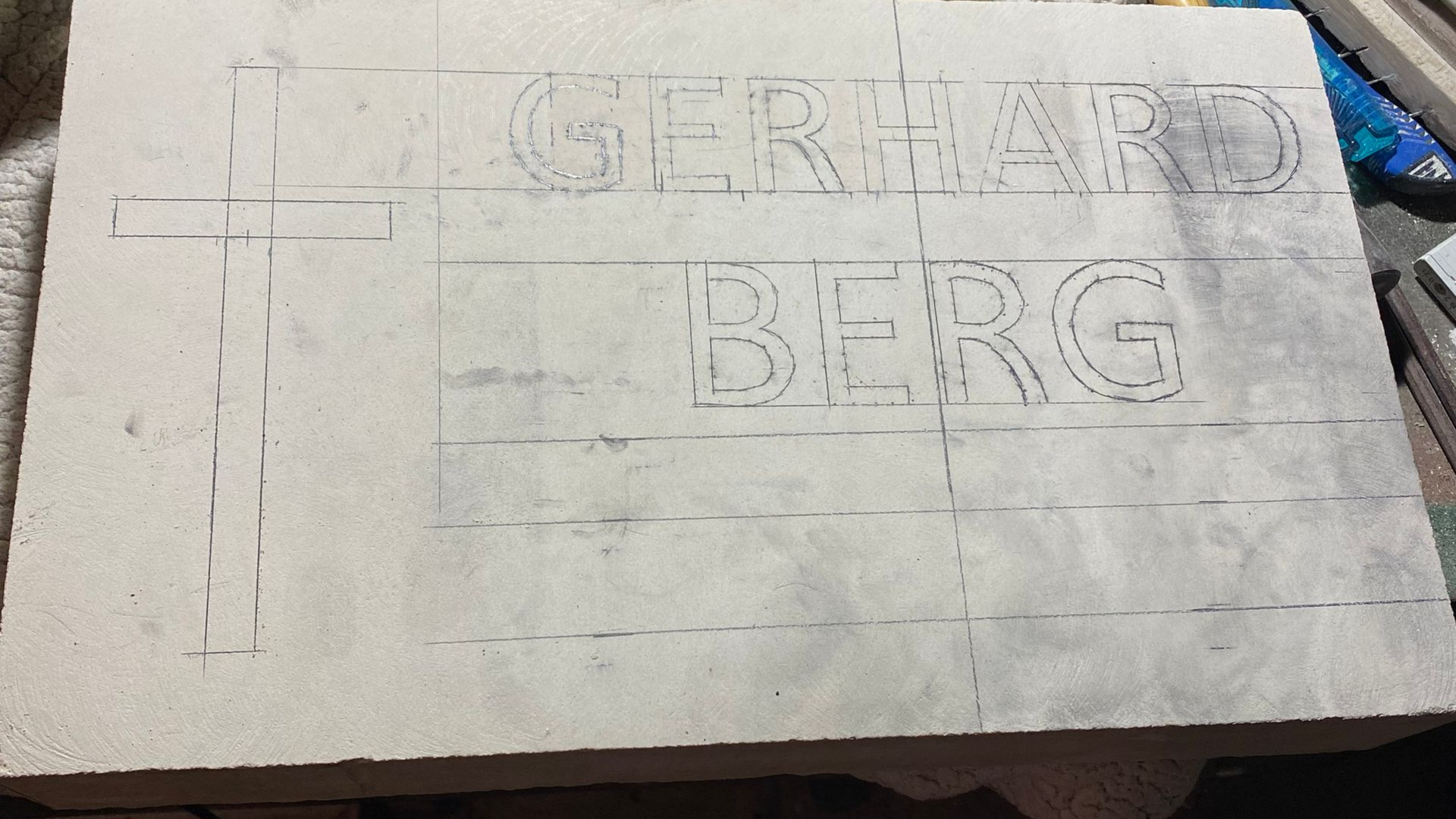 Contours au crayon des mots GERHARD au-dessus de BERG sur une pierre rectangulaire de couleur claire.