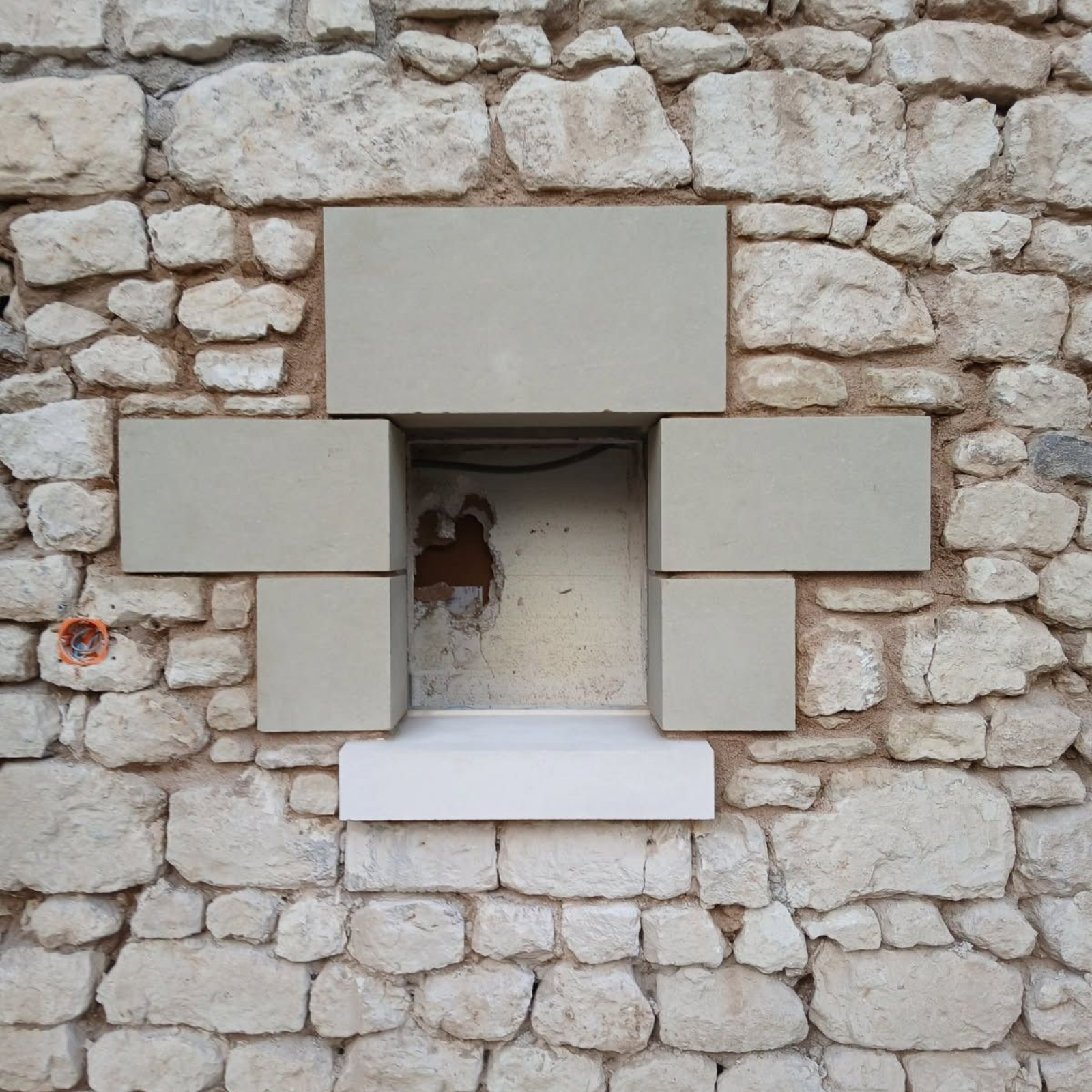 Mur en pierre avec encadrement de fenêtre rectangulaire.
