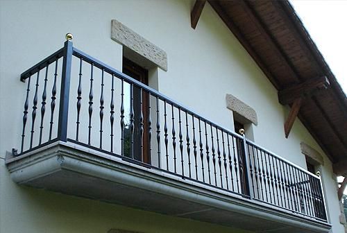 Un balcón en el lateral de un edificio con una barandilla negra.