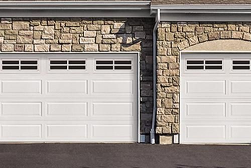 Hay dos puertas de garaje en el lateral de una casa.
