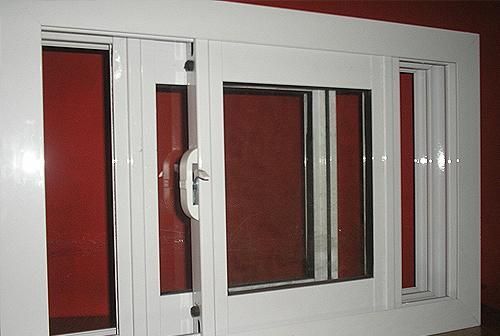 Una ventana blanca con una pared roja al fondo.