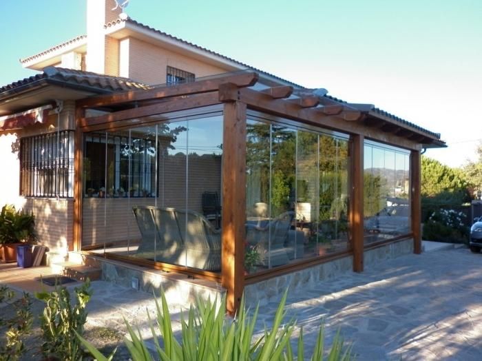 Una casa con pérgola y muchas ventanas.