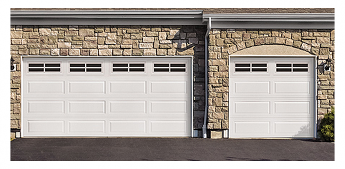 Hay dos puertas de garaje blancas en un edificio de ladrillo.