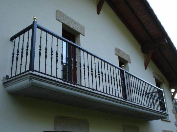 Un balcón en el lateral de un edificio con una barandilla de hierro forjado.