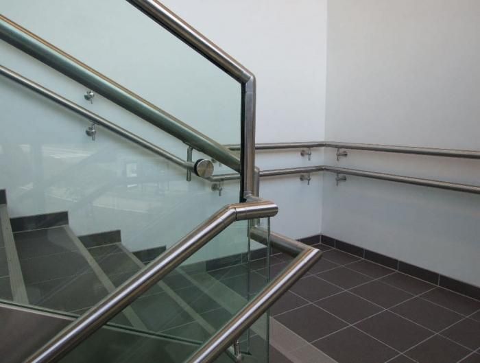 Una escalera con barandilla de acero inoxidable y barandilla de vidrio.