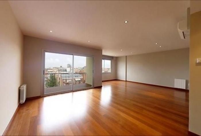 Una sala de estar vacía con pisos de madera y puertas corredizas de vidrio.