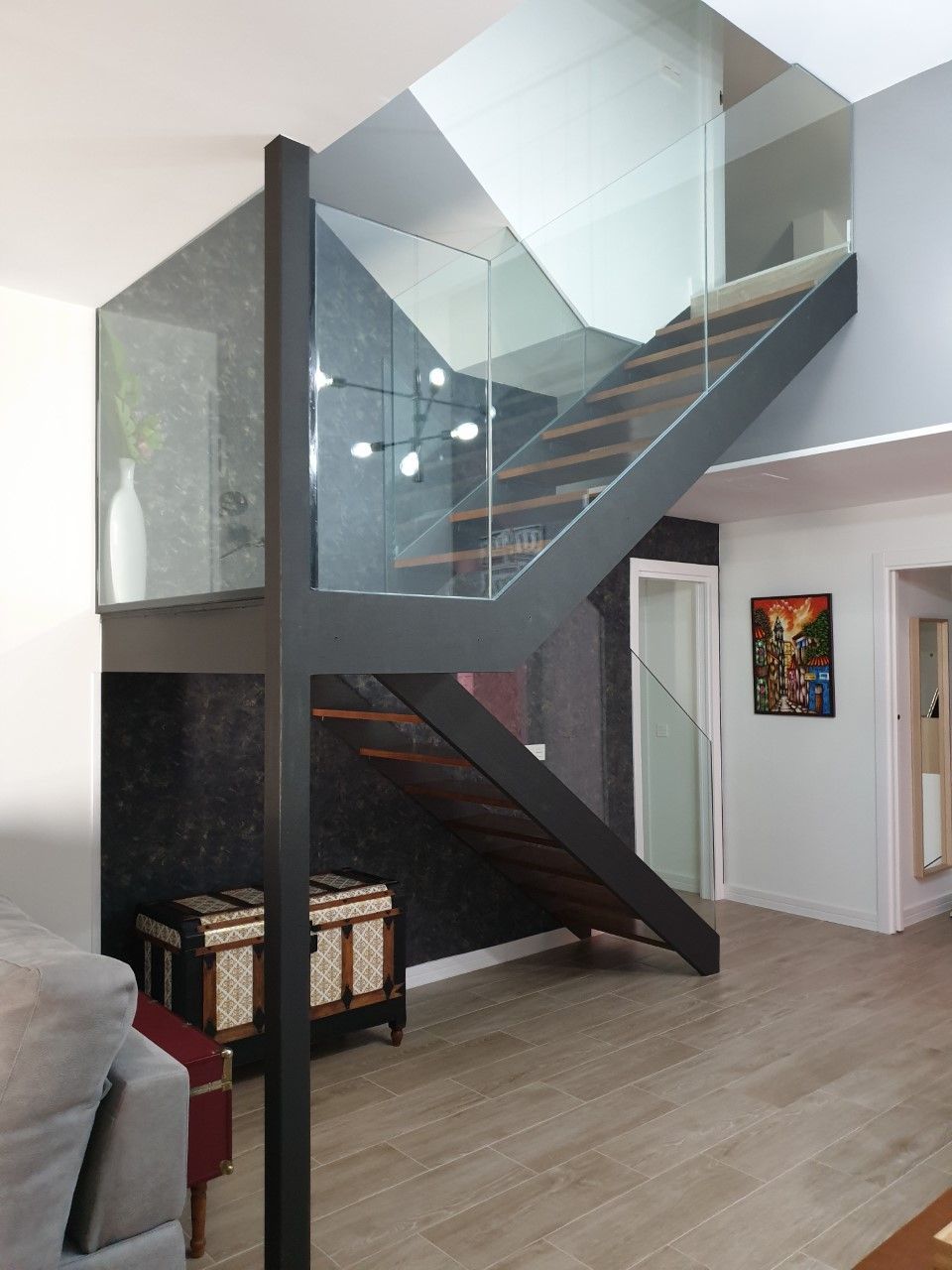 Una sala de estar con escalera y barandilla de cristal.