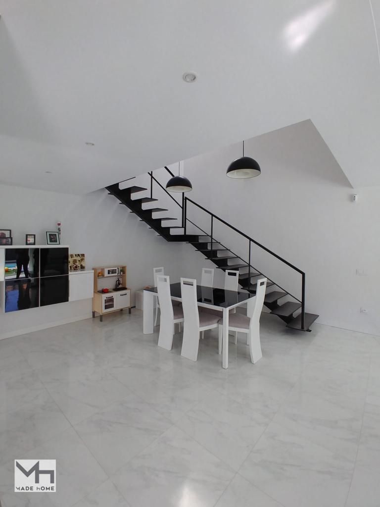 Una sala de estar con una escalera y una mesa y sillas.