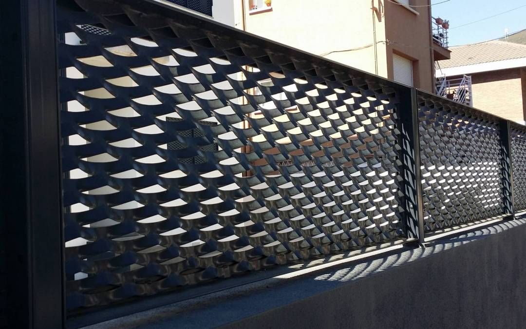 Un primer plano de una valla de metal con una casa al fondo.