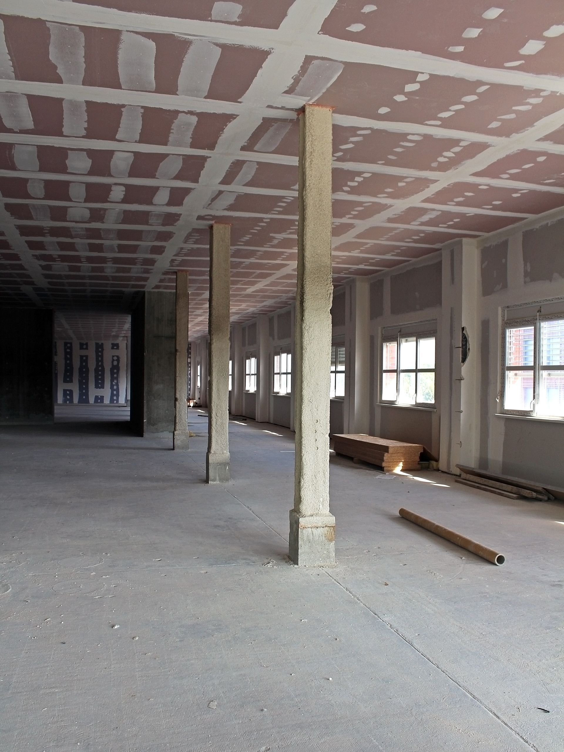 Intérieur d'un bâtiment en construction. Piliers en béton, murs et plafond inachevés, espace vide.