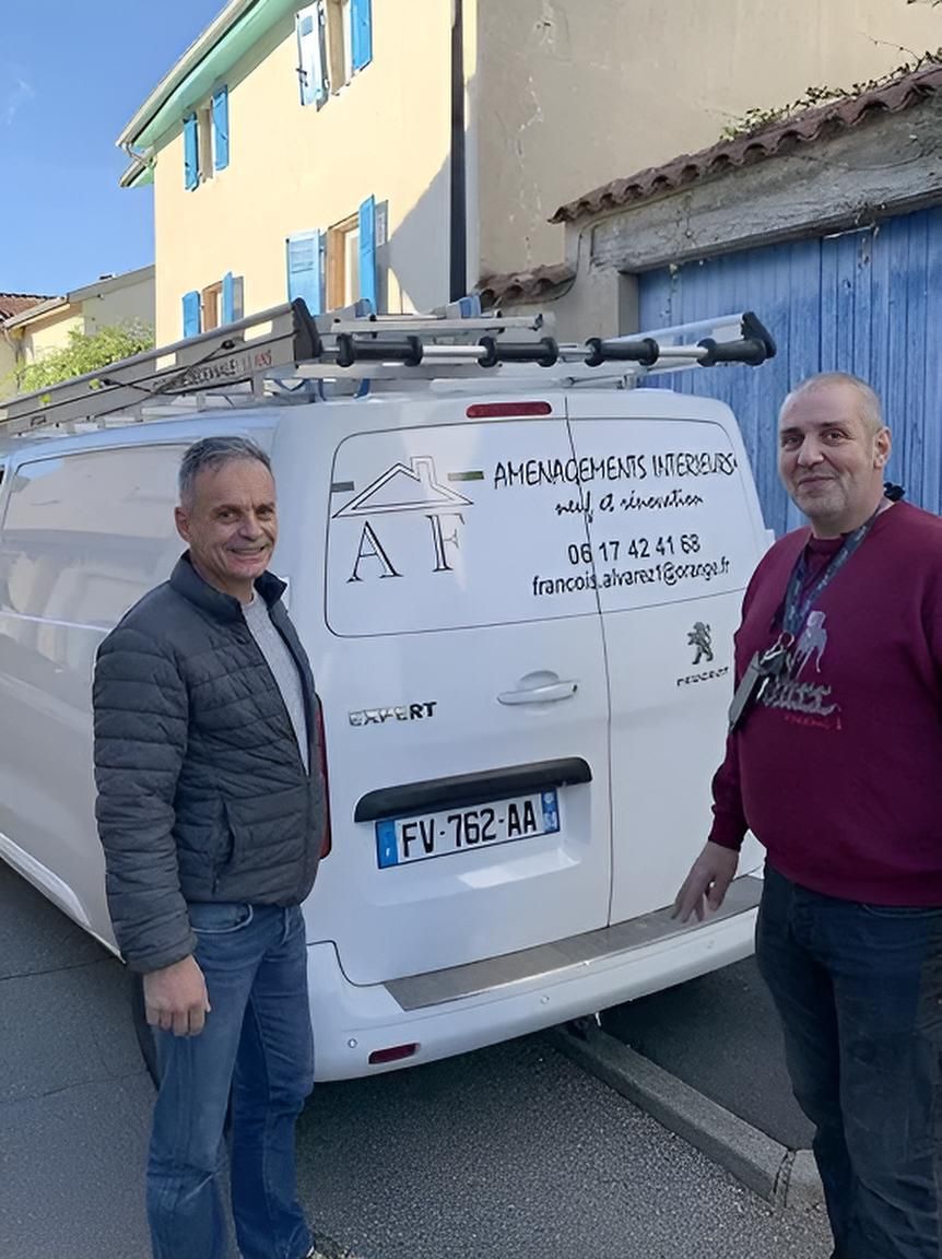 Deux hommes se tiennent à côté d'une camionnette blanche portant le logo de l'entreprise, devant un bâtiment.