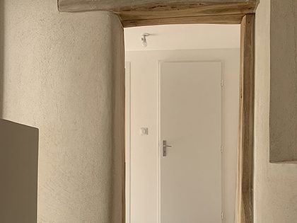 Porte intérieure avec porte blanche, moulures en bois et murs blancs texturés.