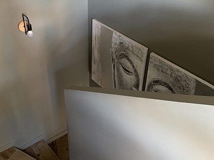 Escalier orné d'un portrait mural. Une applique murale avec une ampoule allumée est fixée au mur.