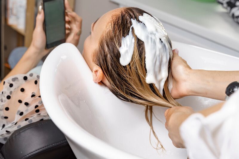 Una mujer con cabello largo y rubio se cubre la cara con su cabello.