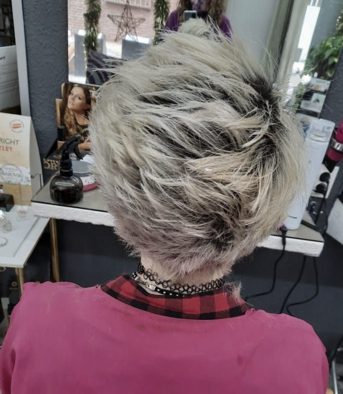 Una mujer con cabello rubio está sentada frente a un espejo.