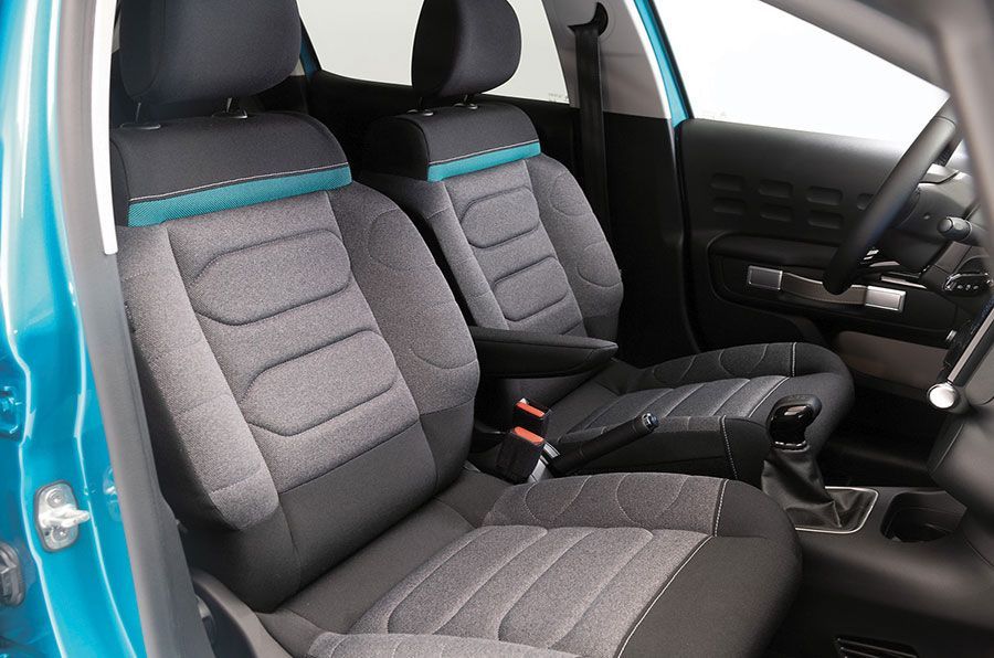 Intérieur de voiture avec sièges gris et noirs et touches turquoise.