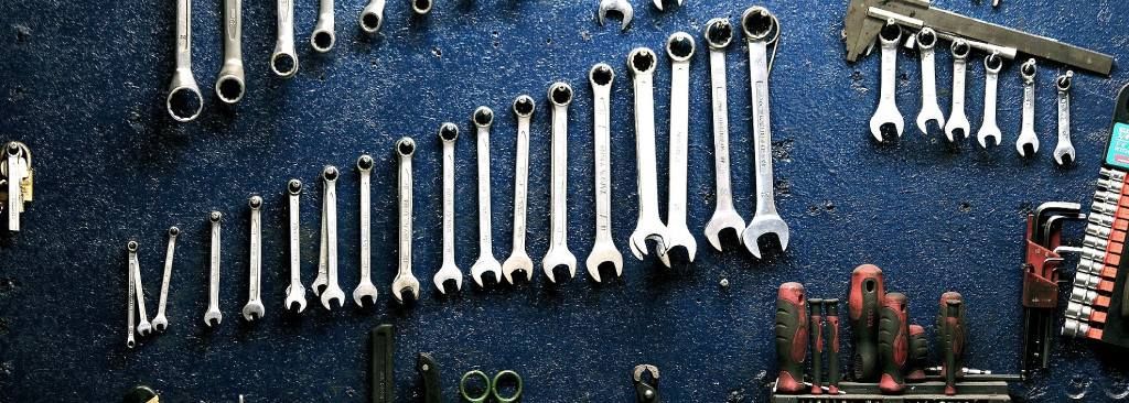 Outils rangés sur un mur bleu : clés et tournevis.