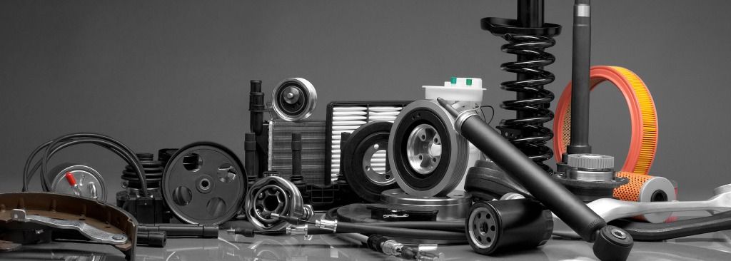 Assortiment de pièces automobiles, comprenant des filtres, des ressorts et des engrenages, disposés sur une surface grise.