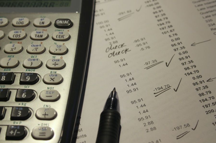 Calculatrice, stylo et document financier contenant des calculs, annoté de coches.