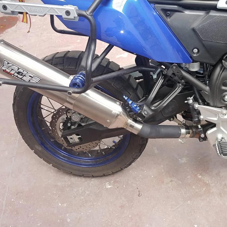 Una motocicleta azul con un tubo de escape de acero inoxidable.
