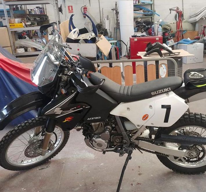 Una moto todoterreno Suzuki está estacionada en un garaje.