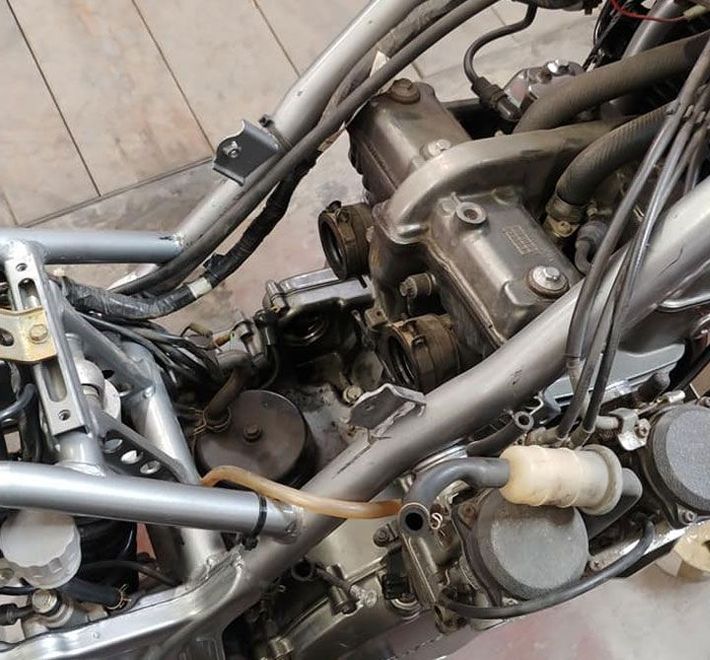 Un primer plano de un motor de motocicleta con una manguera que sale de él.