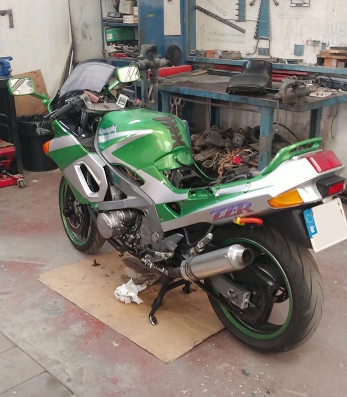 Una motocicleta verde y plateada está estacionada en un garaje.