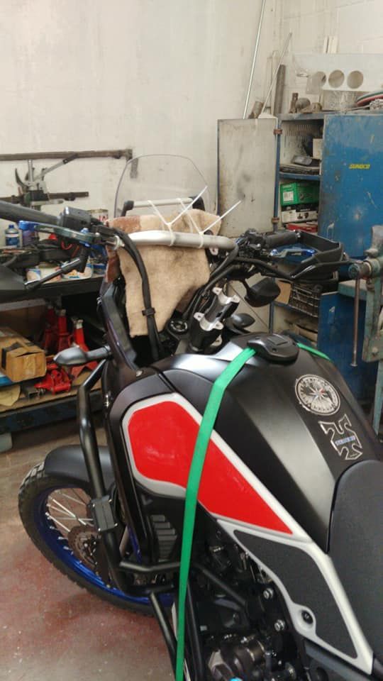 Una motocicleta está parada en un garaje con una correa verde alrededor de ella.