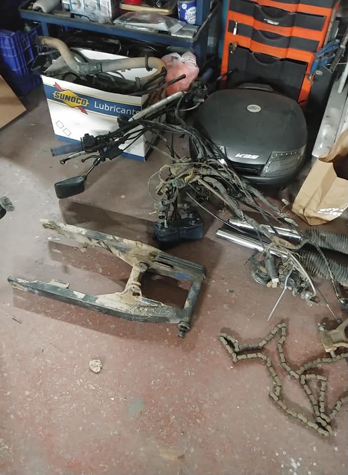 Un montón de piezas de motocicletas están tiradas en el suelo de un garaje.