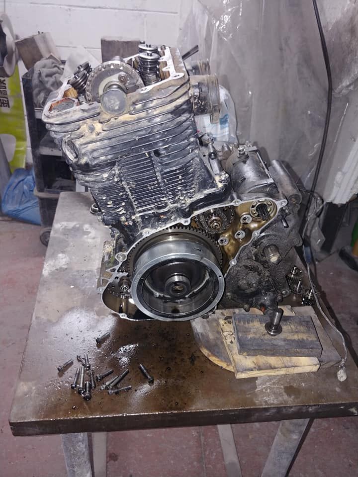 Un motor de motocicleta está sentado encima de una mesa de madera.