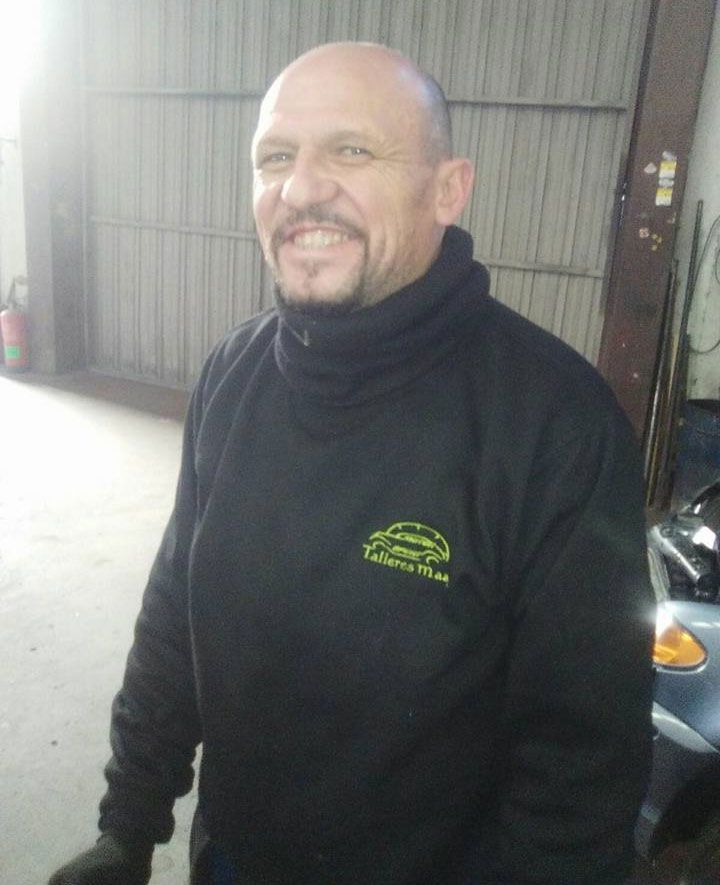 Un hombre calvo con barba lleva un suéter negro con un logo verde en el frente.