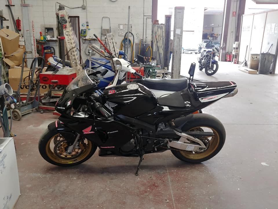 Una motocicleta negra está estacionada en un garaje con otras motocicletas.