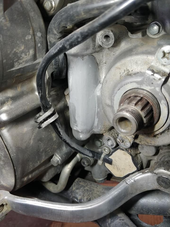 Un primer plano de un motor de motocicleta con un pedal de freno.