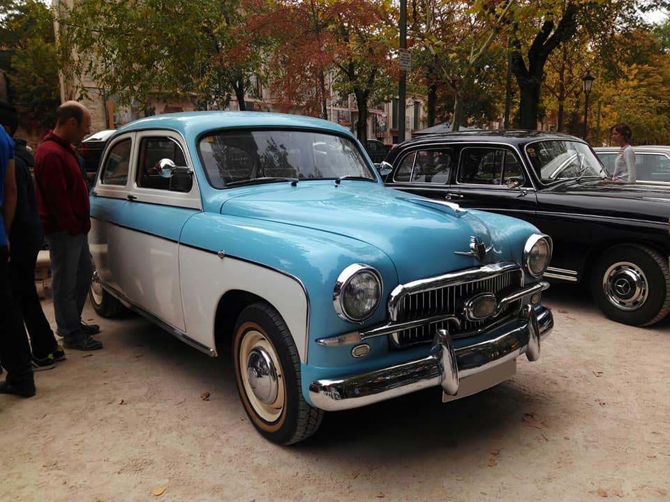 Un coche azul y blanco está aparcado en un estacionamiento.