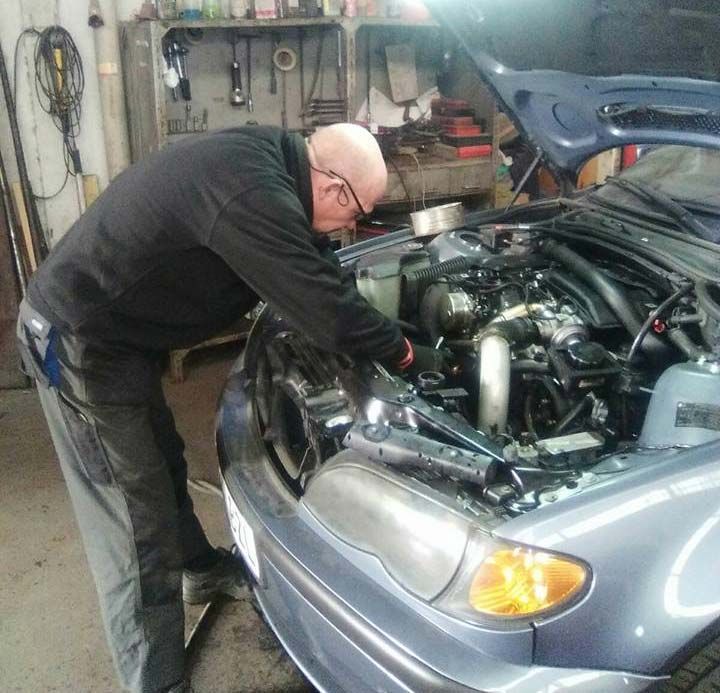 Un hombre mirando debajo del capó de un coche