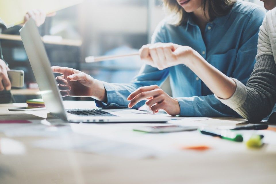 Kaksi ihmistä tekee yhdessä töitä kannettavalla tietokoneella.