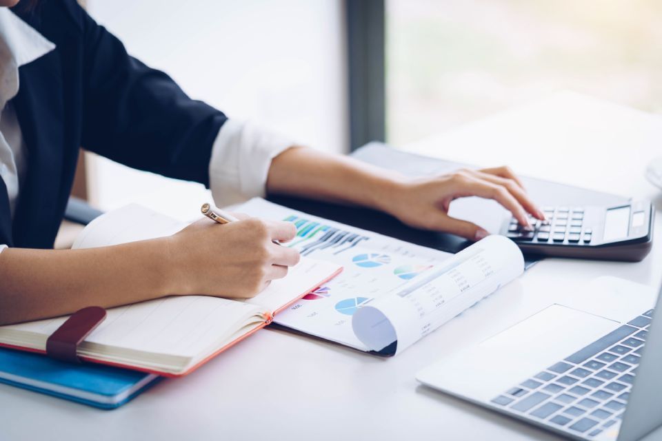 Henkilö tekee muistiinpanoja ja laskee laskimella.