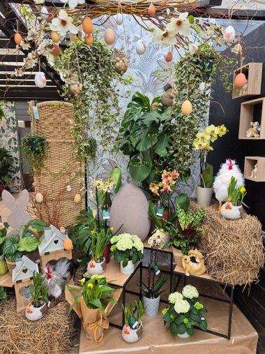 Une décoration de Pâques festive avec des plantes en pot, des œufs décoratifs, des silhouettes de lapins en bois et des bottes de foin.
