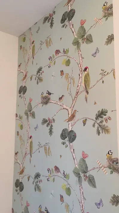 Eine Wand mit einem Gemälde von Vögeln und Blumen darauf.